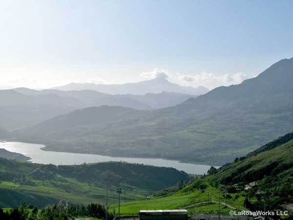 Misty hills beyond a lush river valley in Sicily.